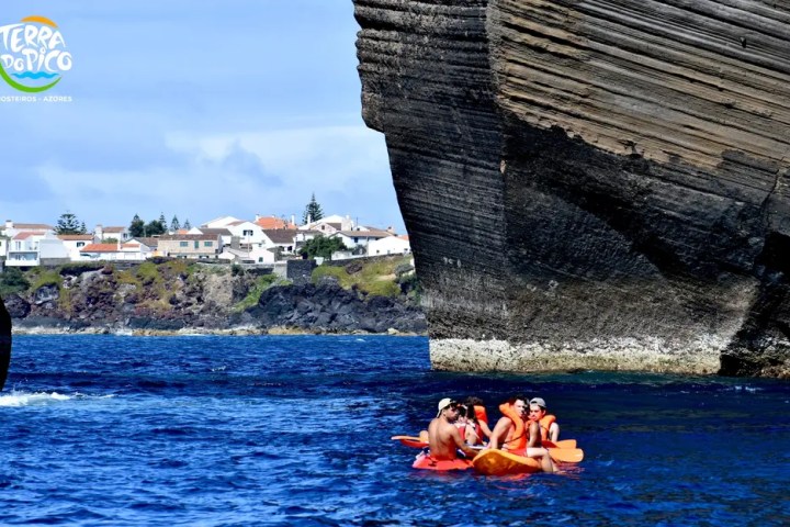 Group kayaking near a large rock formation with a town in the background.