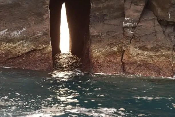 Narrow rock opening with ocean waves in the foreground.